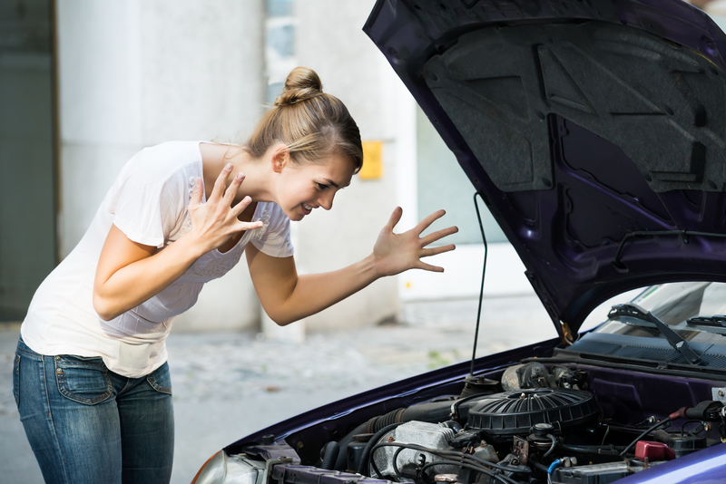Frustrated Woman Looking At Broken Down Car Engine